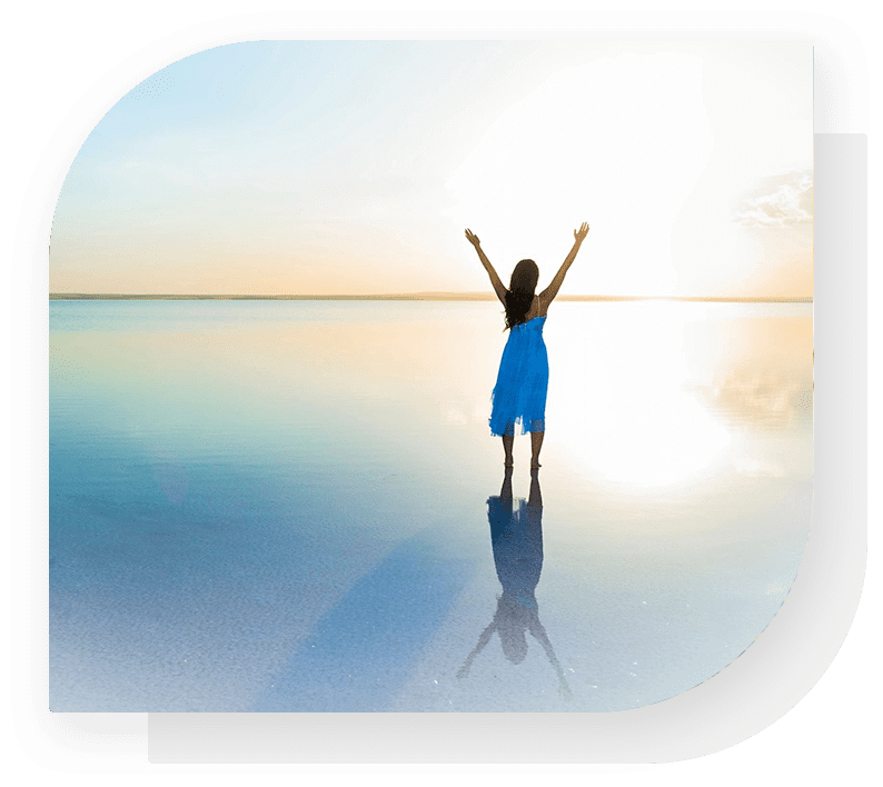 A woman standing on the beach with her arms up.